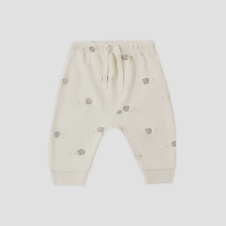 Off-white baby jogger pants with a small gray hedgehog print, featuring an elastic waistband with a drawstring and ribbed ankle cuffs, shown flat on a light gray background.