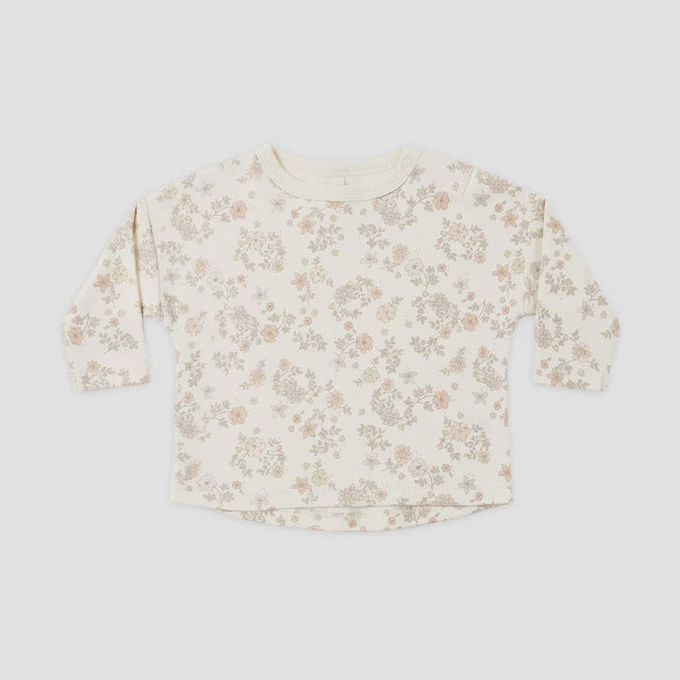 A long-sleeve crewneck top for toddlers, featuring an all-over delicate floral print in muted pink and beige on an off-white base, laid flat against a light gray background.