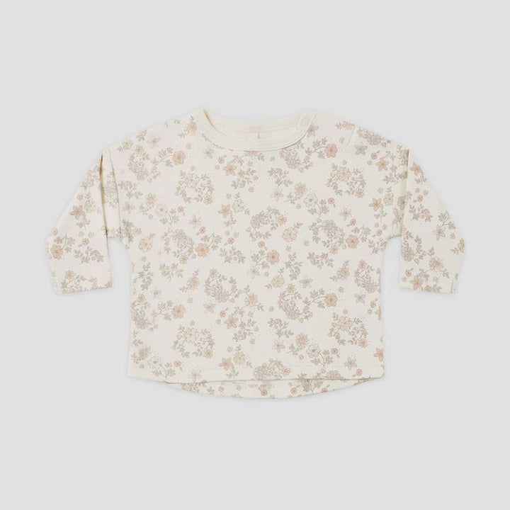 A long-sleeve crewneck top for toddlers, featuring an all-over delicate floral print in muted pink and beige on an off-white base, laid flat against a light gray background.