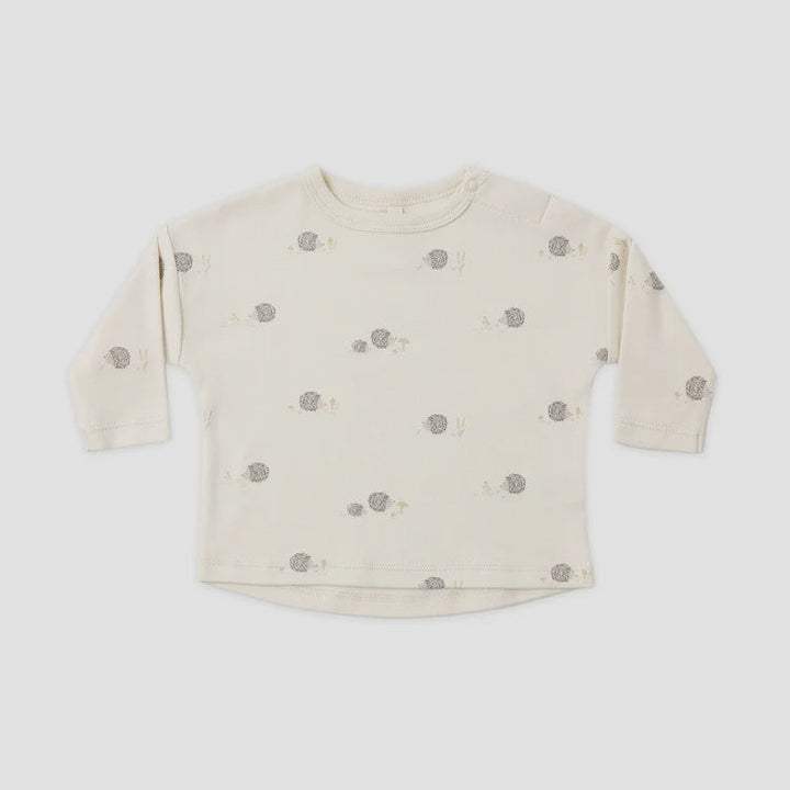 A cream-colored long-sleeve baby top with a small gray and beige animal print, laid flat against a light gray background.