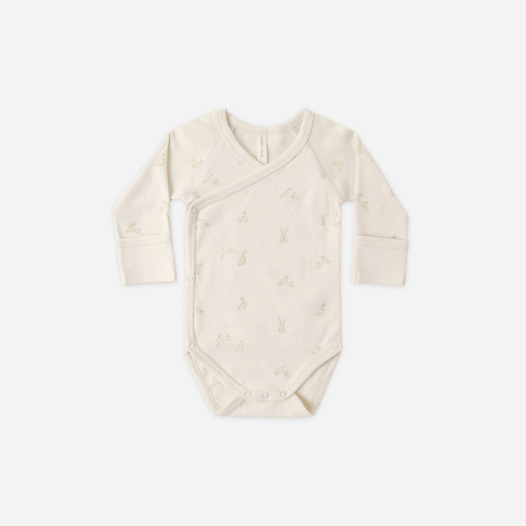 Beige baby bodysuit with long sleeves on a white background