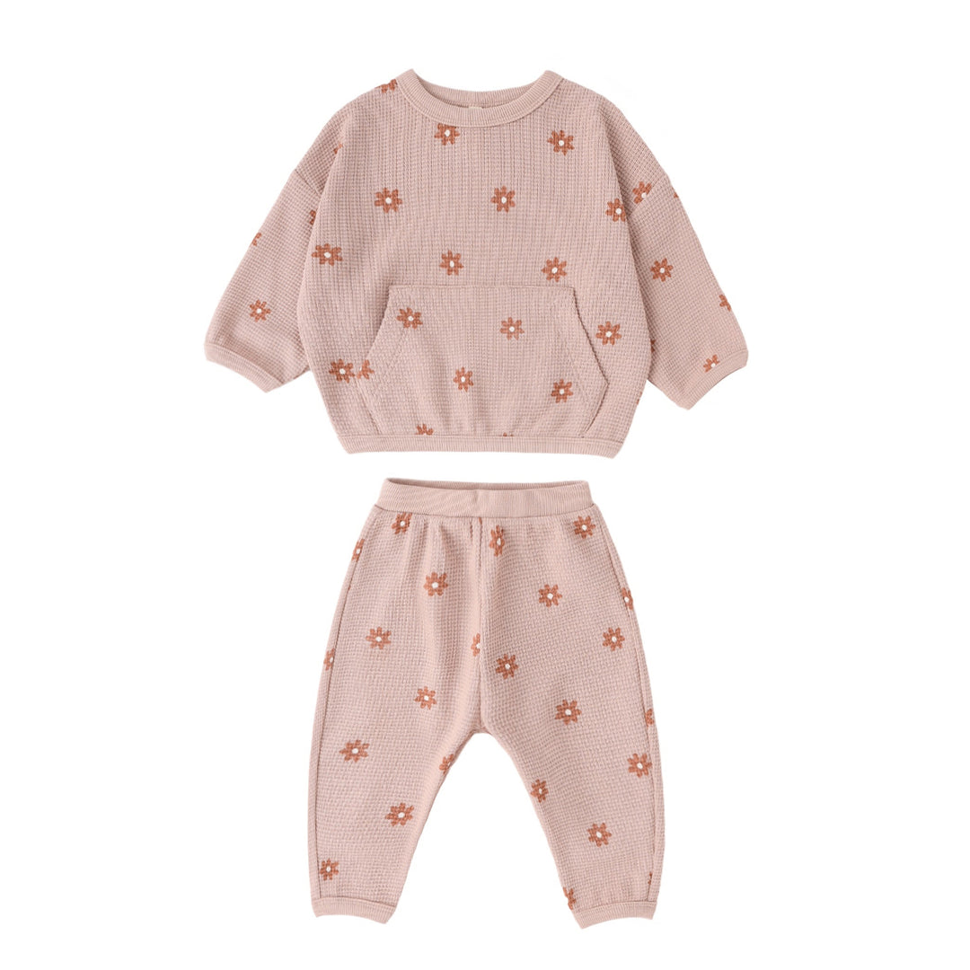 Pink children's outfit with floral patterns on a white background