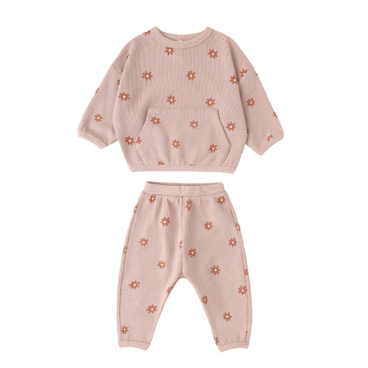 Pink children's outfit with floral patterns on a white background