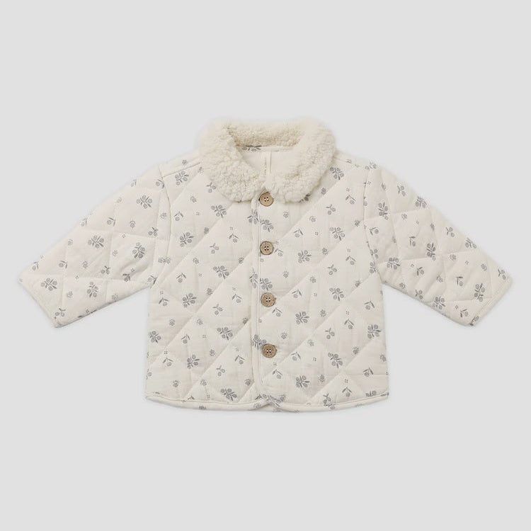 A baby quilted jacket in cream with a small gray floral pattern, featuring a fluffy cream collar and three brown buttons down the front, laid flat on a light gray background.