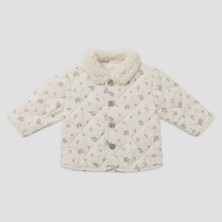 A baby quilted jacket in cream with a small gray floral pattern, featuring a fluffy cream collar and three brown buttons down the front, laid flat on a light gray background.