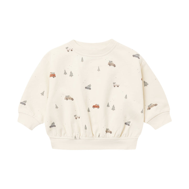 An off-white long-sleeve sweatshirt for toddlers, featuring a playful all-over print of small brown trucks, gray trees, and tiny red accents, displayed on a clean white background.
