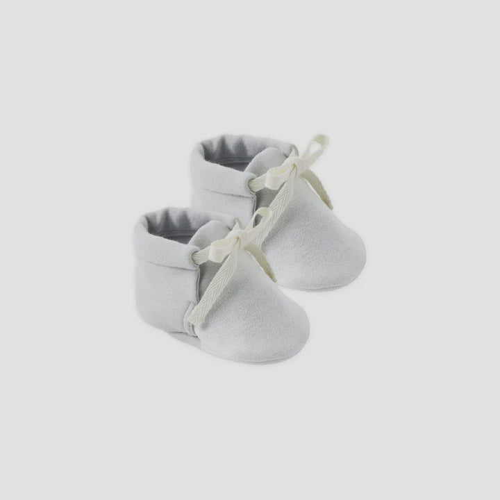 Pair of gray baby shoes with white laces on a light gray background