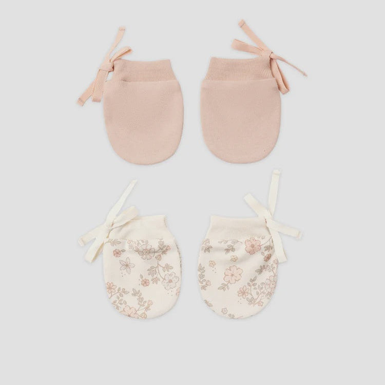 Four baby booties arranged in a 2x2 grid on a light gray background. The top pair is a solid pale blush pink, and the bottom pair is cream with a delicate pink floral pattern and cream ribbon ties.
