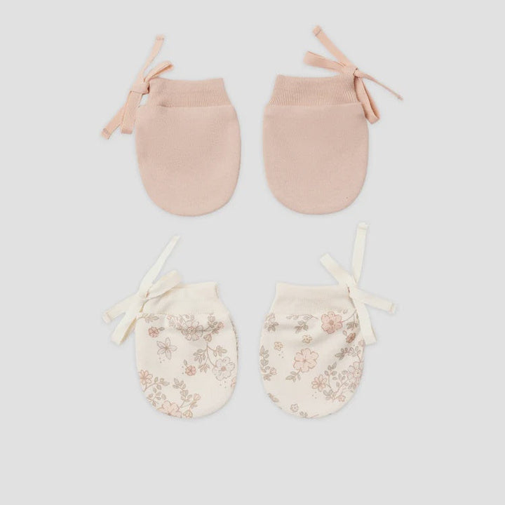 Four baby booties arranged in a 2x2 grid on a light gray background. The top pair is a solid pale blush pink, and the bottom pair is cream with a delicate pink floral pattern and cream ribbon ties.