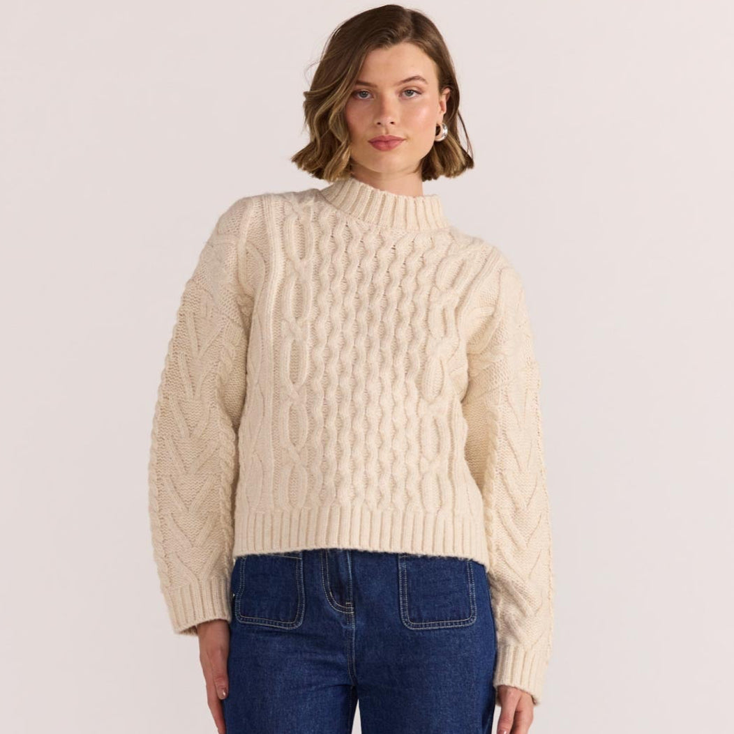 Chunky, cosy, and a cold-weather classic - the Rosina Cable Knit Jumper in cream is your go-to for elevated everyday warmth. Available from www.thecollectivenz.com