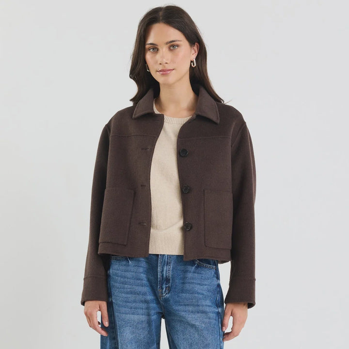 Woman wearing a brown jacket and blue jeans on a white background