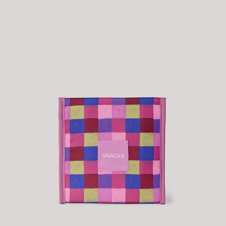 A pink and purple checkered snack pouch with a small pink label reading 'SNACKS' on the front, set against a solid light gray background.