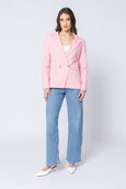 Woman wearing a pink blazer and blue jeans on a white background