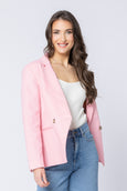 Woman wearing a pink seeking lola blazer over a white top and blue jeans on a light gray background