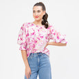 Woman wearing a pink floral blouse and blue jeans on a white background