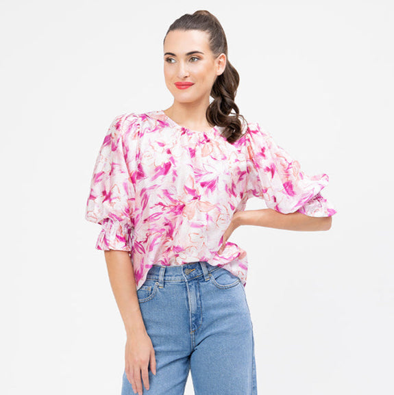 Woman wearing a pink floral blouse and blue jeans on a white background