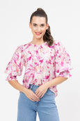 Woman wearing a pink floral blouse and blue jeans on a white background