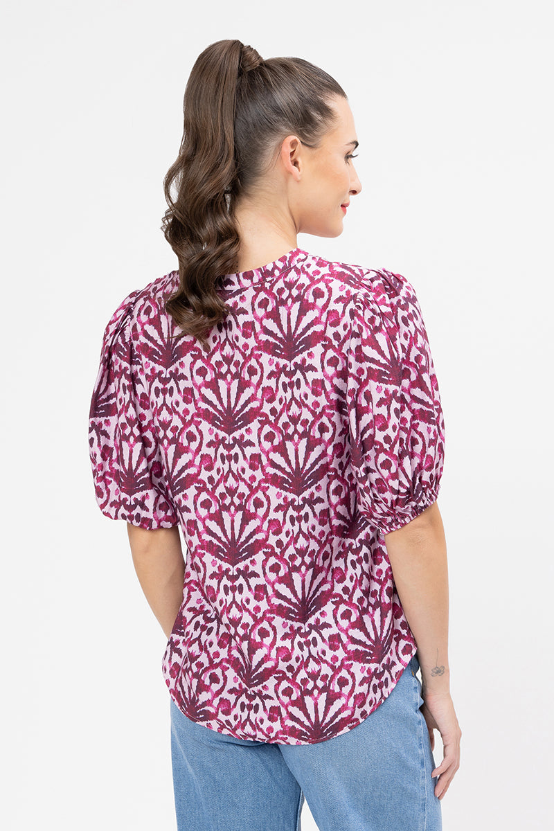 Woman wearing a pink patterned blouse with blue jeans on a white background