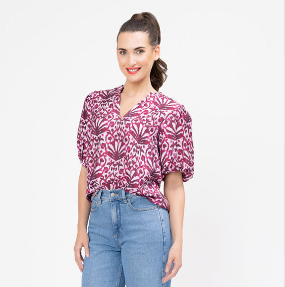 Woman wearing a patterned blouse and blue jeans on a white background