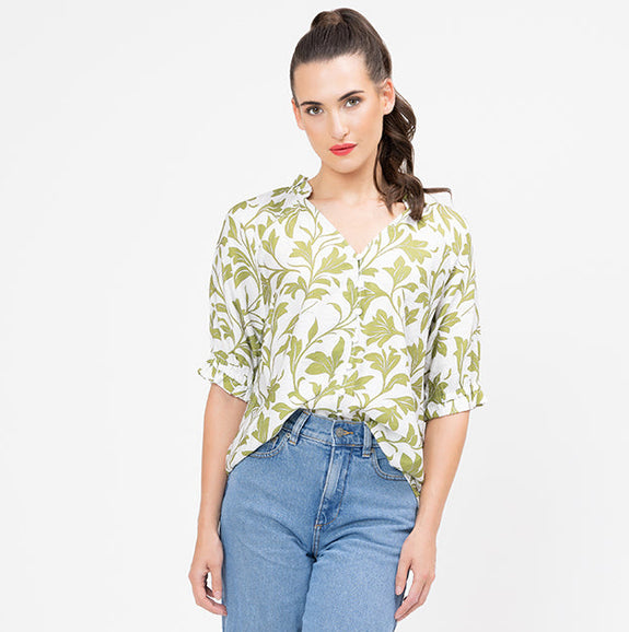 Woman wearing a floral seeking lola blouse and blue jeans on a white background