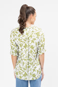 Woman wearing a seeking lola green and white floral patterned shirt on a white background