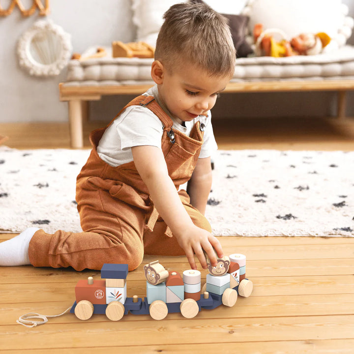 Child playing with a wooden toy train on a wooden floor.