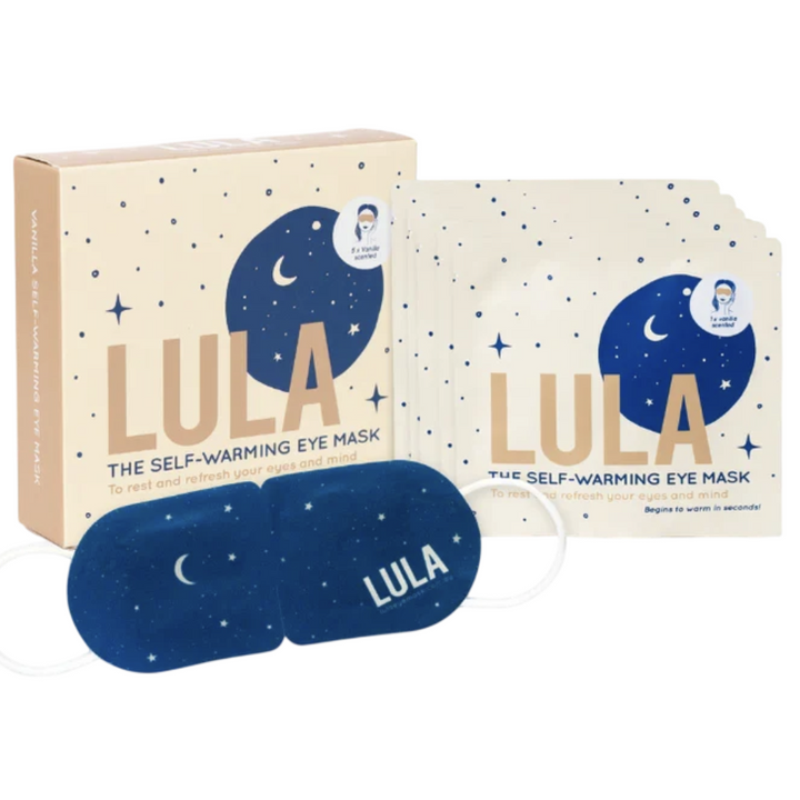 LULA self-warming eye mask set with a cream-colored box, a stack of individual packet sleeves, and one blue sleep mask decorated with a starry night sky pattern.