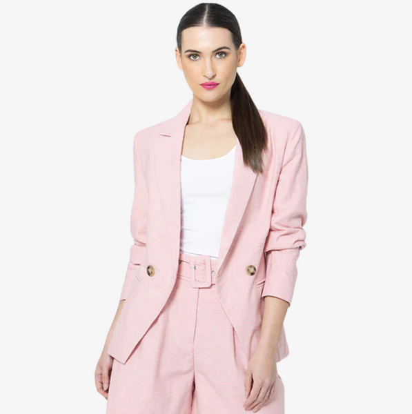 Woman wearing a pink seeking lola blazer on a white background