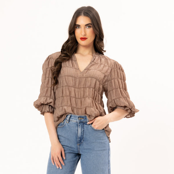 Woman wearing a brown blouse and blue jeans on a white background