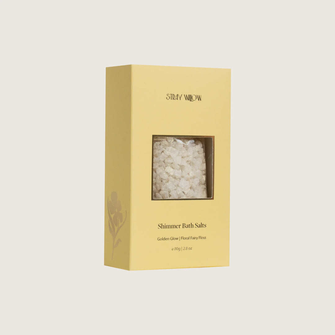 Yellow box of Shimmer Bath Salts with clear window showing contents on a light beige background