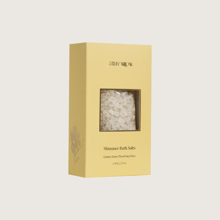 Yellow box of Shimmer Bath Salts with clear window showing contents on a light beige background