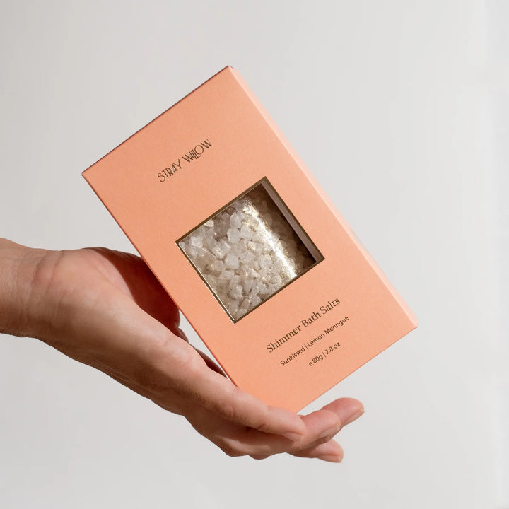Hand holding a box of Shimmer Bath Salts by Story & Moon on a light gray background
