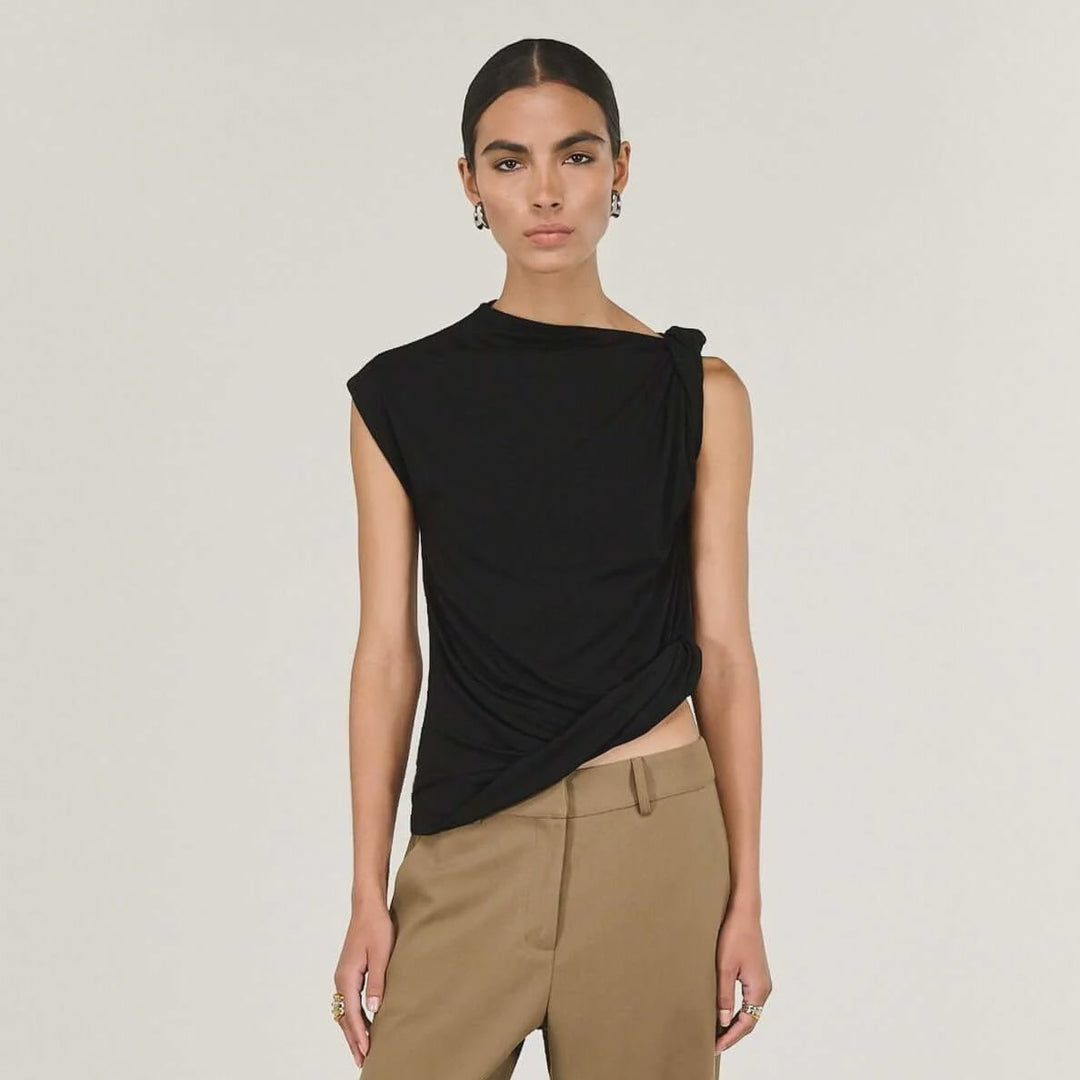 Woman wearing a black sleeveless top and beige pants on a white background