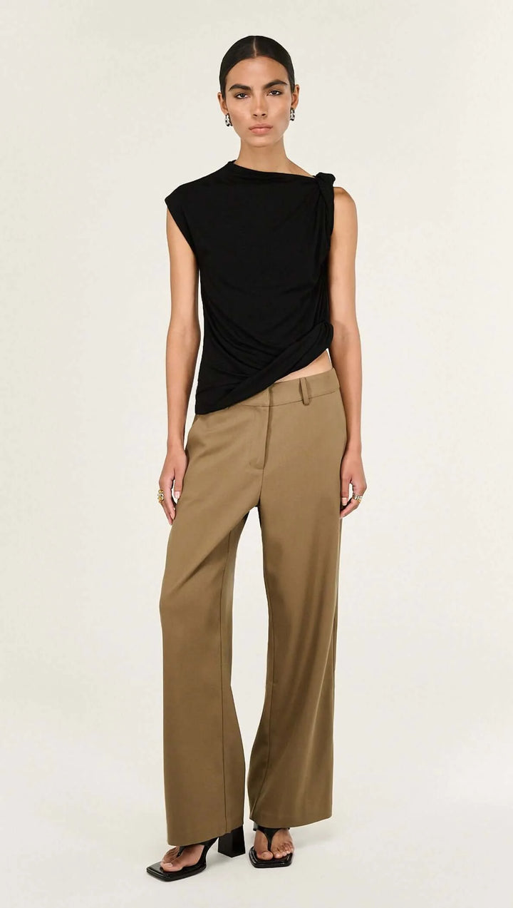 Woman wearing a black sleeveless top and beige pants on a white background