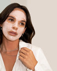 Woman applying a facial mask with a neutral background