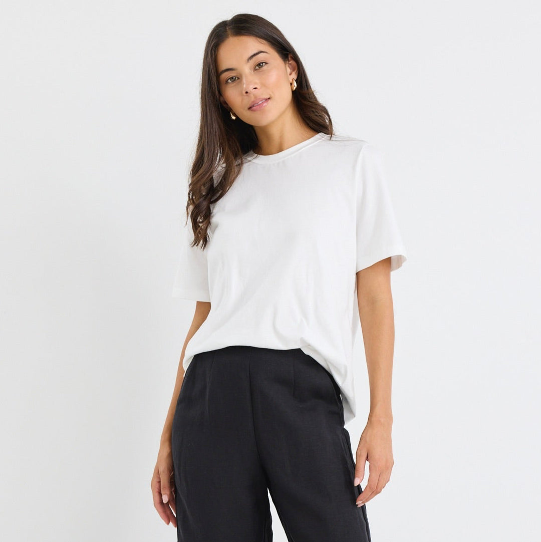 Woman wearing a white top and black wide-leg pants on a white background