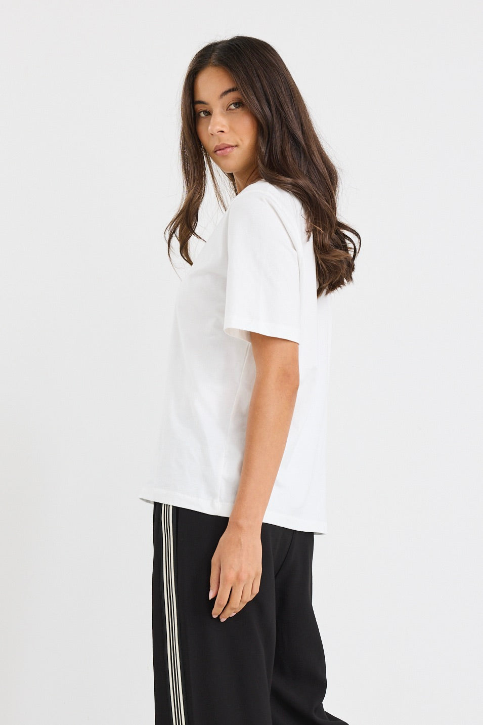 Person wearing a white t-shirt and black pants with stripes on a white background