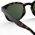 Sunglasses with tortoiseshell frame and green lenses on a white background