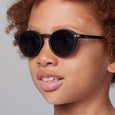Close-up of a person wearing black sunglasses with a neutral background