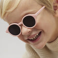 Child wearing pink sunglasses with a plain background
