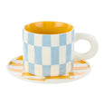 Colorful checkered mug and saucer on a white background