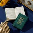 Small open book with a pen and decorative elements on a blue surface