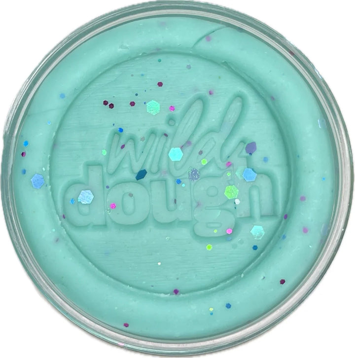 Turquoise-colored pot of 'wild dough' with colorful specks on a white background