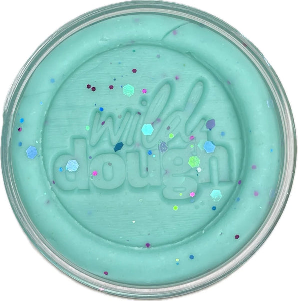 Turquoise-colored pot of 'wild dough' with colorful specks on a white background