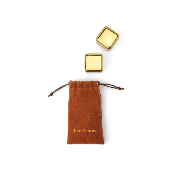 Two gold square-shaped cocktail chillers on a white background with a brown drawstring bag.