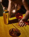 Person holding a cocktail glass with a red drink on a gold table, next to a cocktail shaker.