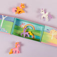 Toy unicorns on a colorful book with a rainbow and castle illustration.