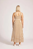 Woman wearing a eb and ive striped dress with a plain background