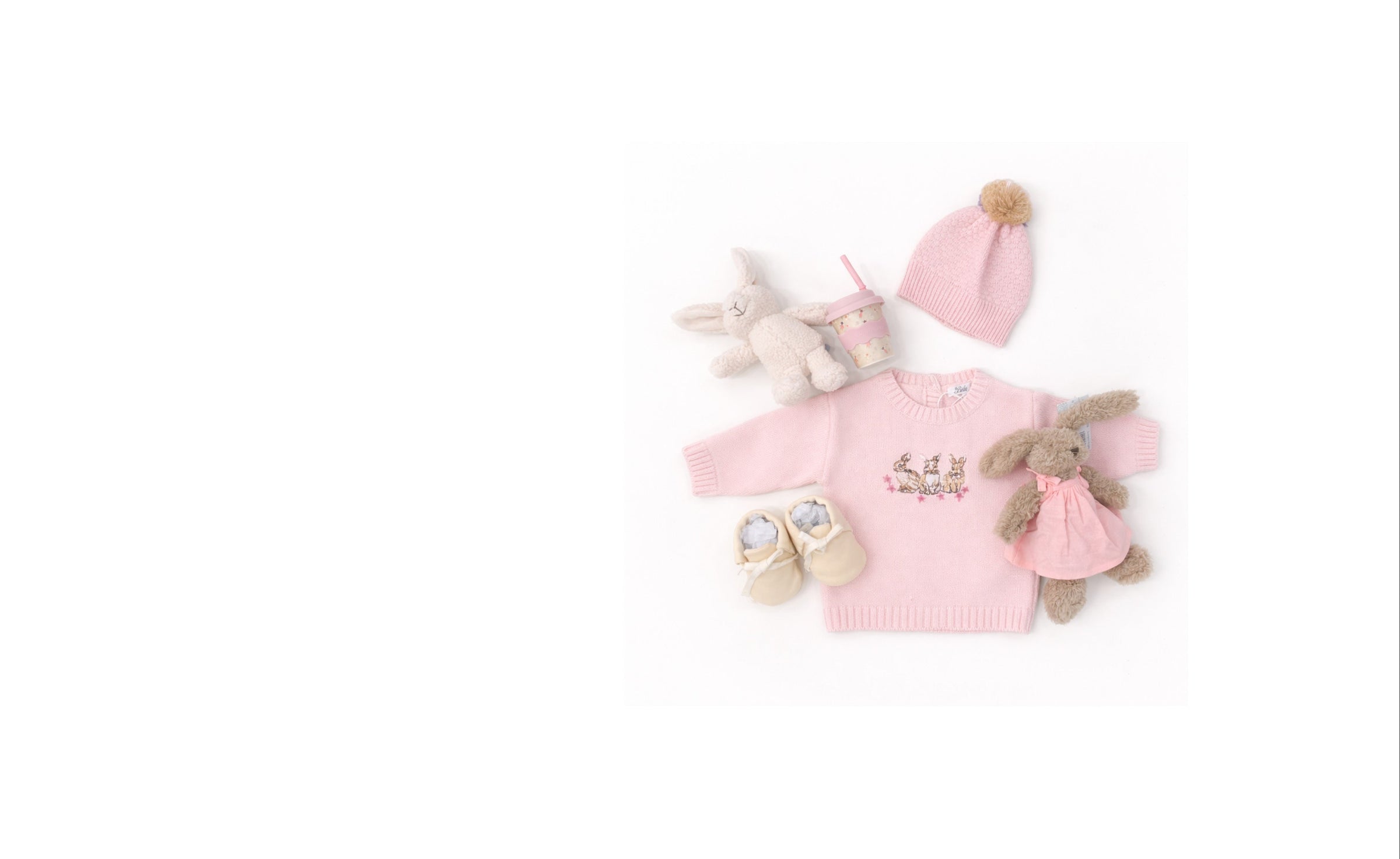 Pink baby outfit with hat, blanket, and toys on a white background