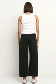 Person wearing a white sleeveless top and black wide-leg pants on a white background